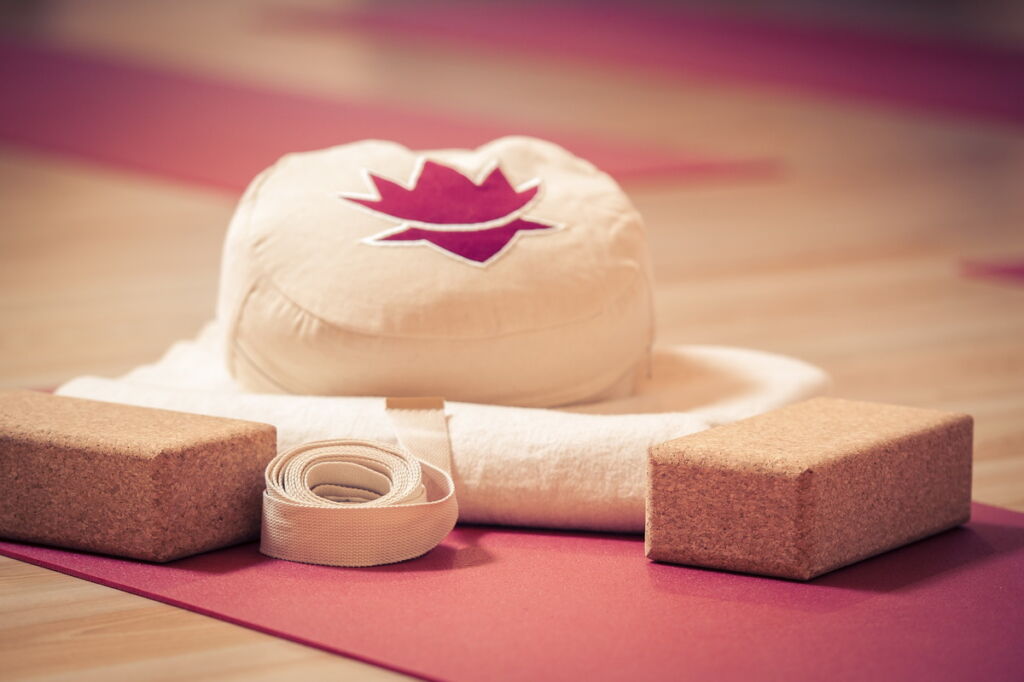 Utensilien für einen Yogakurs: Yogaklötze, Yogamatte, Yogagurt, eine Decke