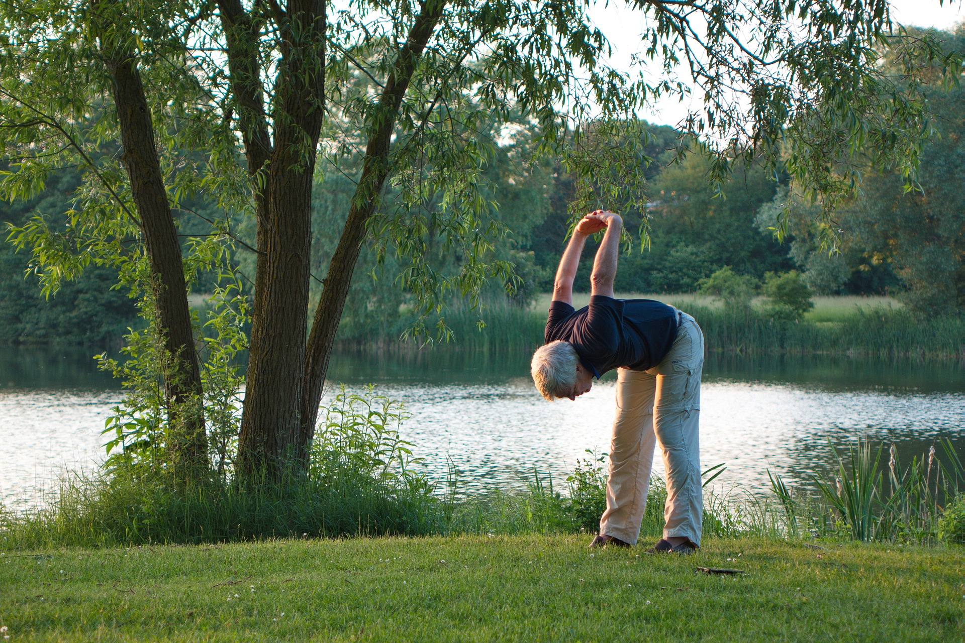 Ein älterer Mann, der in der Natur Yoga praktiziert